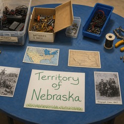 Telegraph parts and Territory of Nebraska materials on a blue table